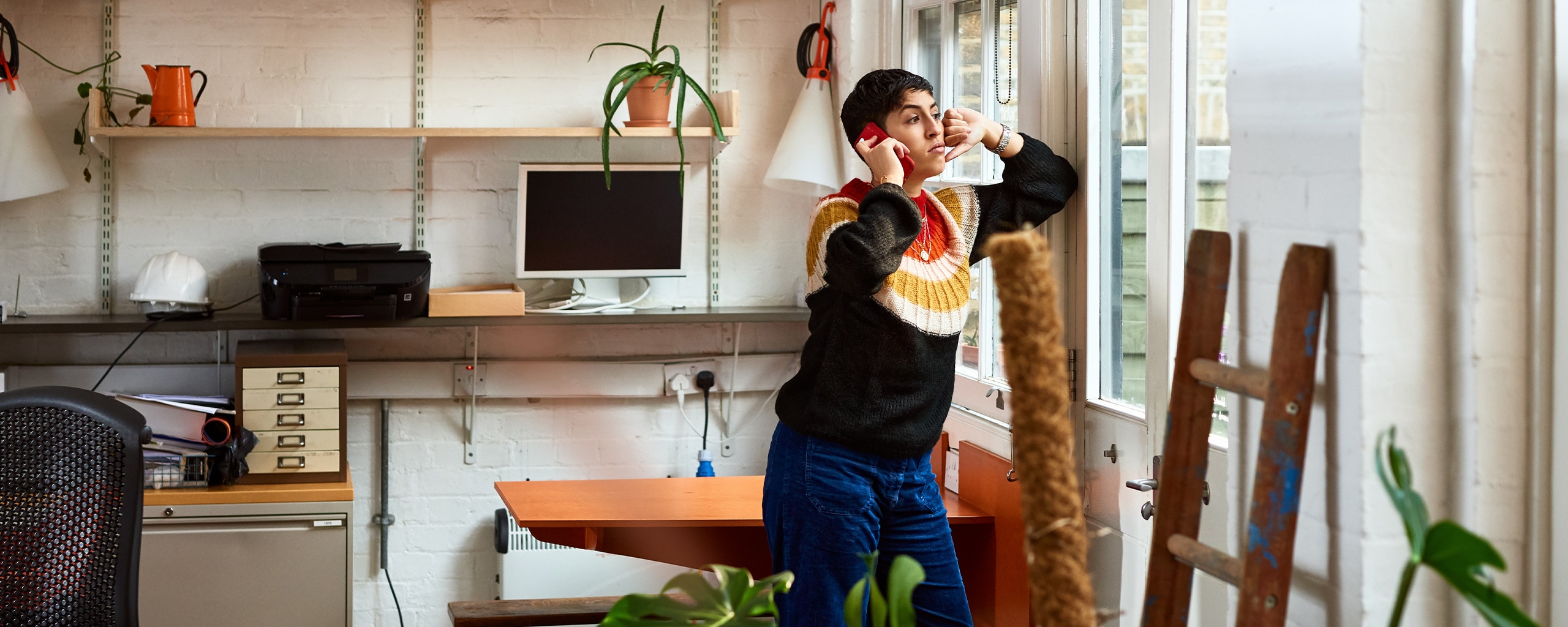 A photo of a person at home, using their mobile phone to make a call about paying off debt.