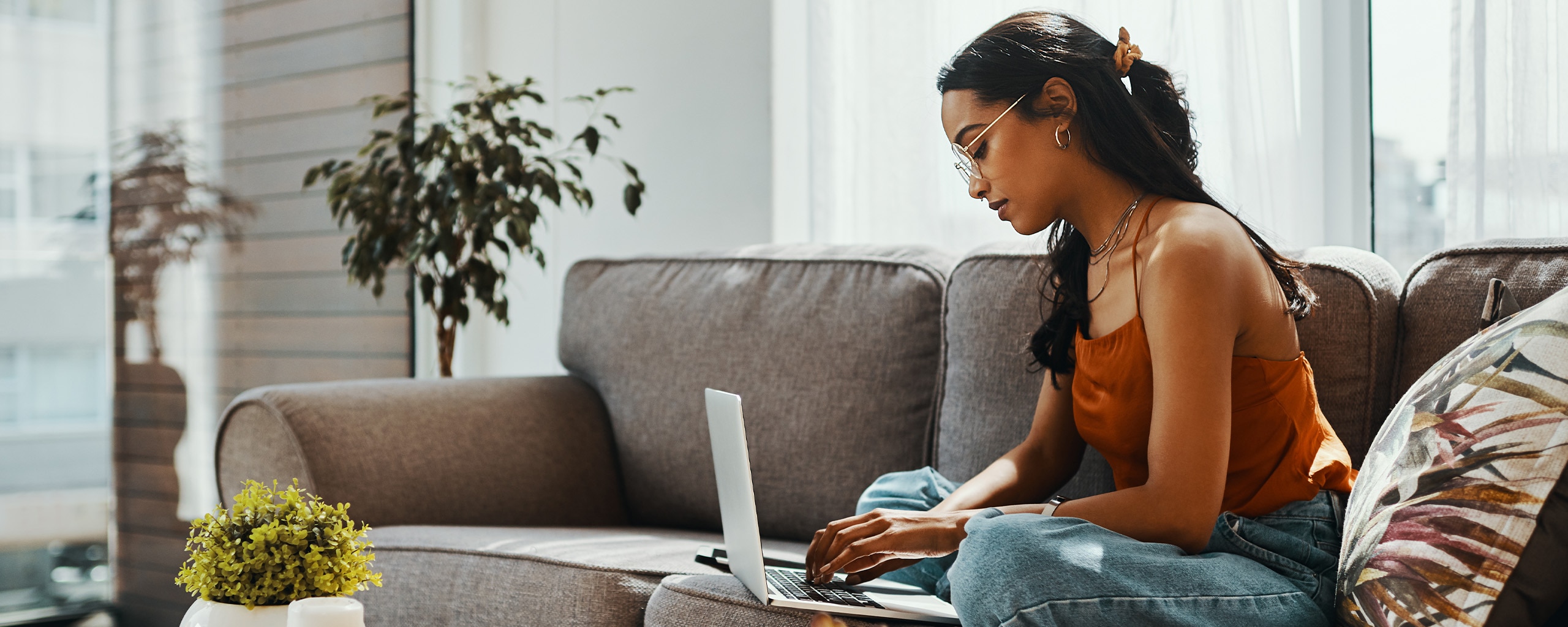 A person sits on the couch and looks at their credit information on a laptop.
