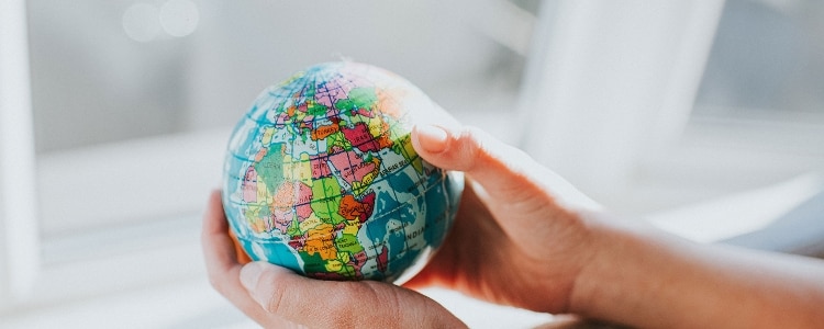 A person holds a small globe in their hands while researching other countries that have credit scores.