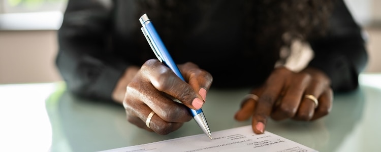 A person signs over a check with a blue pen.