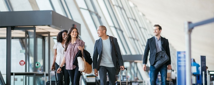 A group of people with luggage walk through an airport.