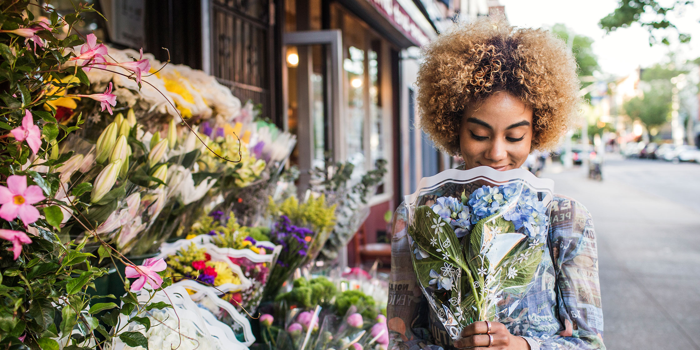 A person holds a bouquet of flowers outside a flower market.