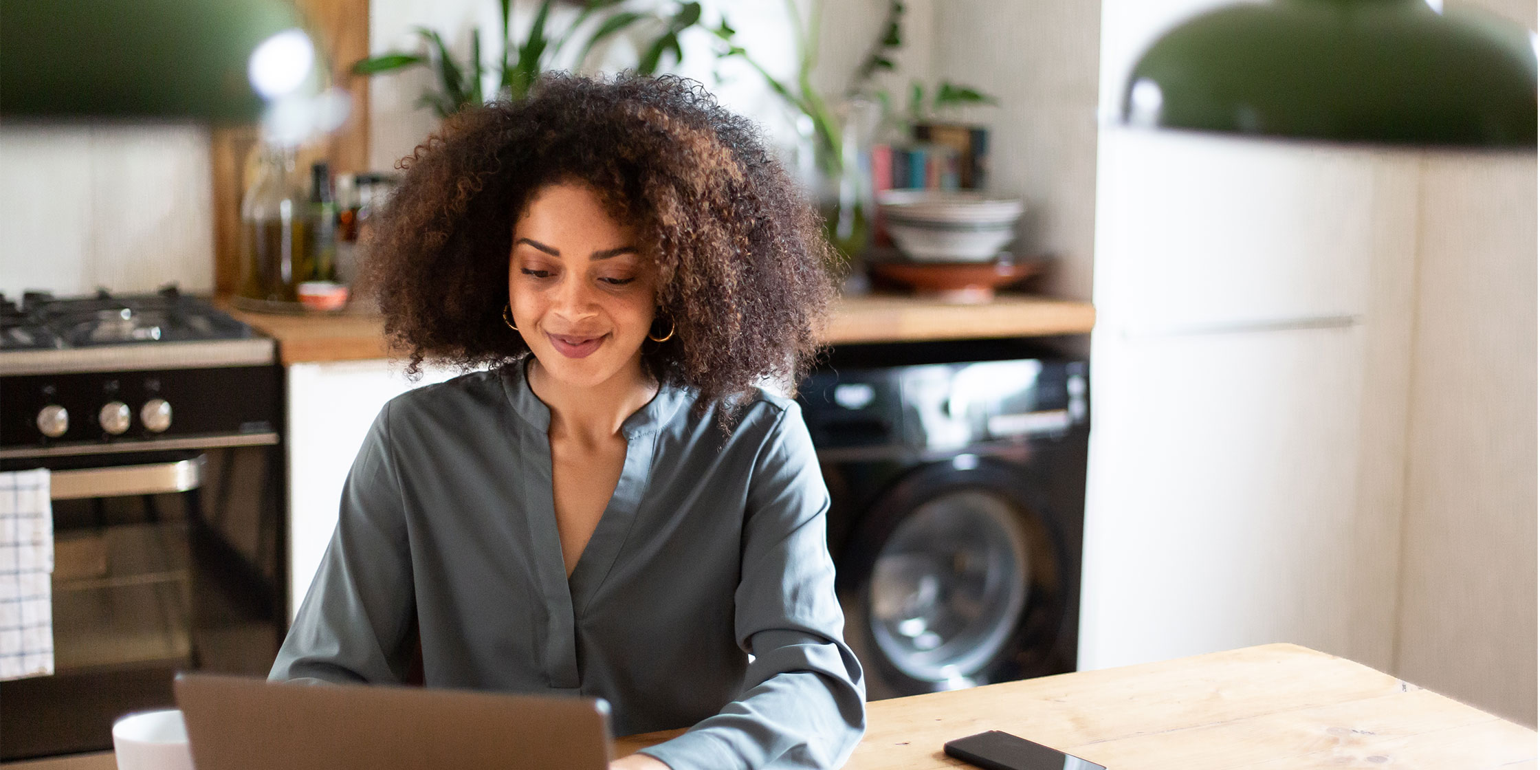 A person sitting at a kitchen table reads about what an annual percentage rate (APR) is on a laptop.