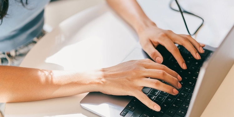 A person types on a keyboard to freeze their credit with Equifax online.