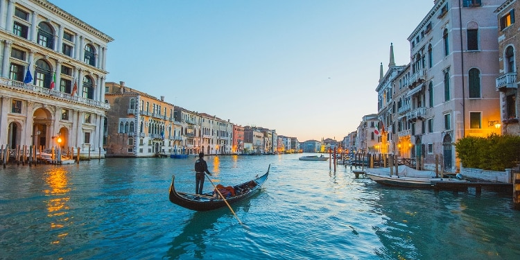 A gondolier rowing down a canal in Venice, Italy.