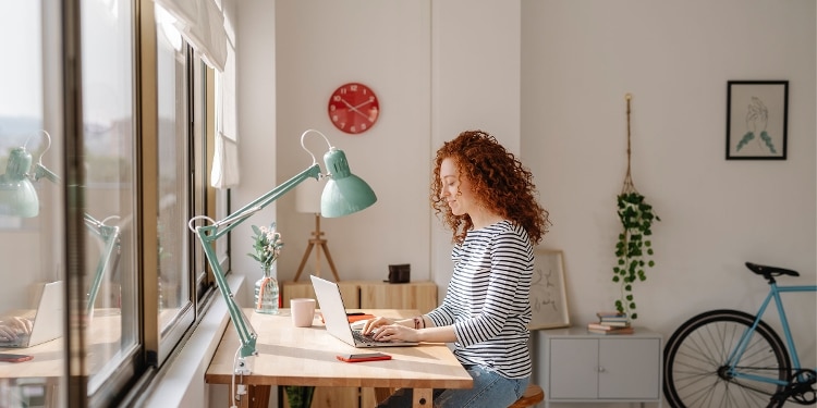 A person sits in front of a laptop to learn about self-reporting to credit bureaus.