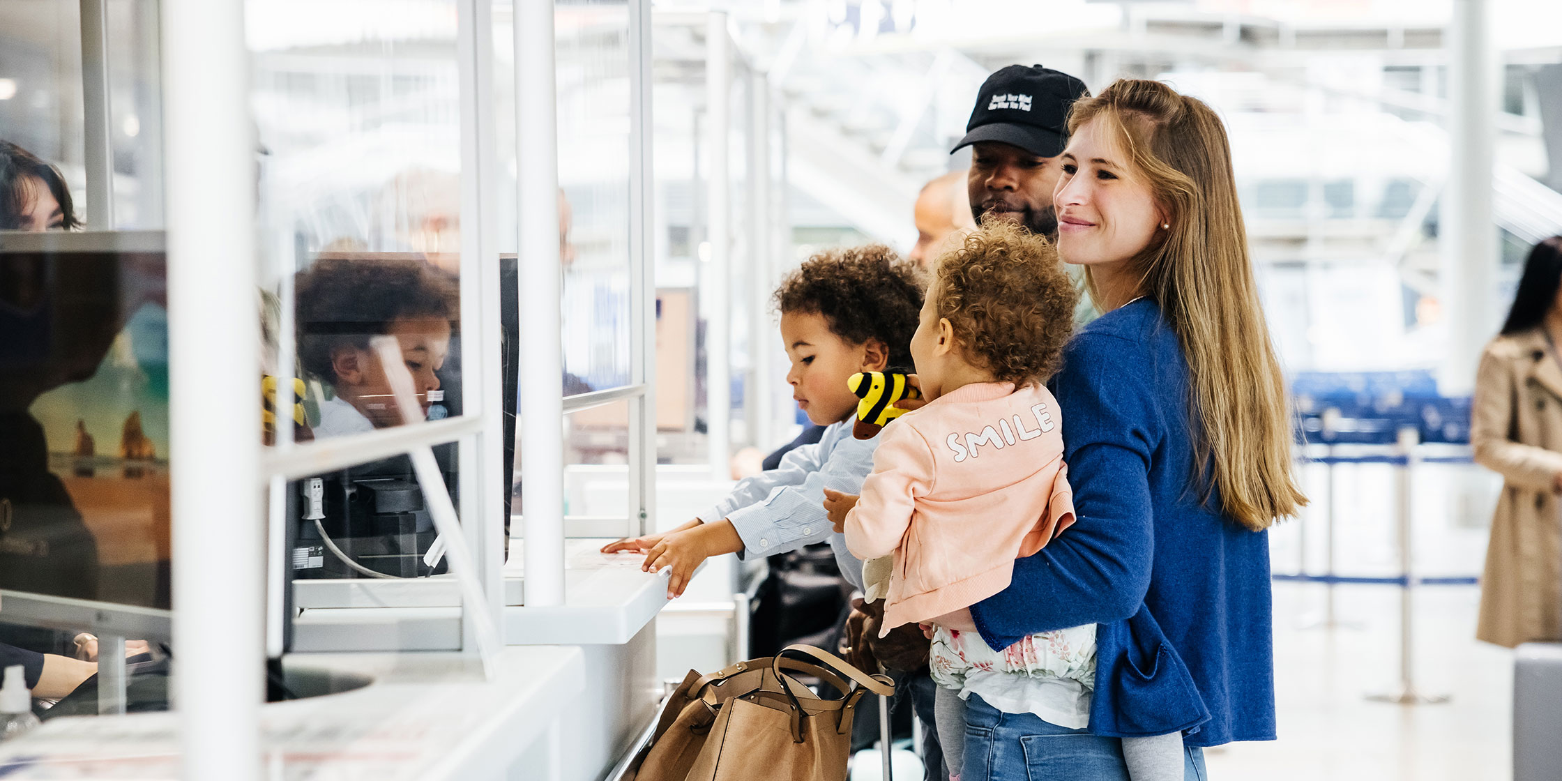 Two parents juggle their children as they navigate airport security.