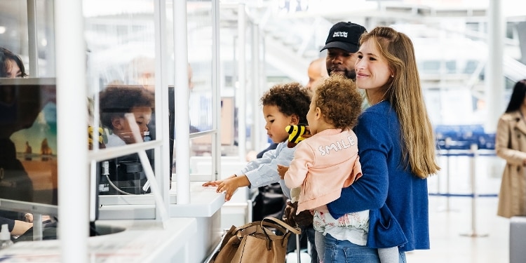 Two parents juggle their children as they navigate airport security.