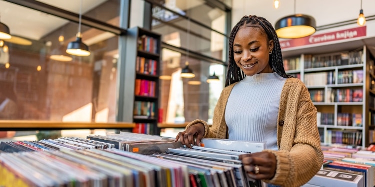 A smiling person browses the vinyl collection at a record store.