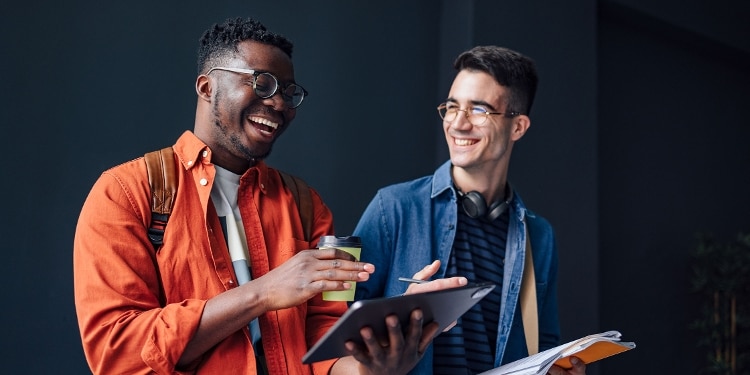 Two college students laughing together while walking to class.