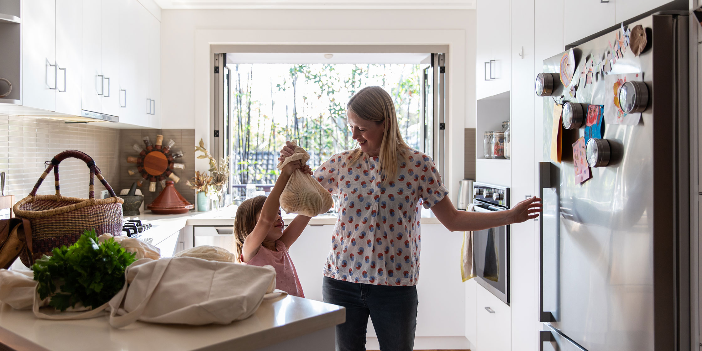 Child helps her mom put groceries in the refrigerator.