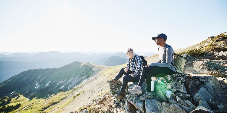 Two smiling backpackers resting during a hike in the mountains.