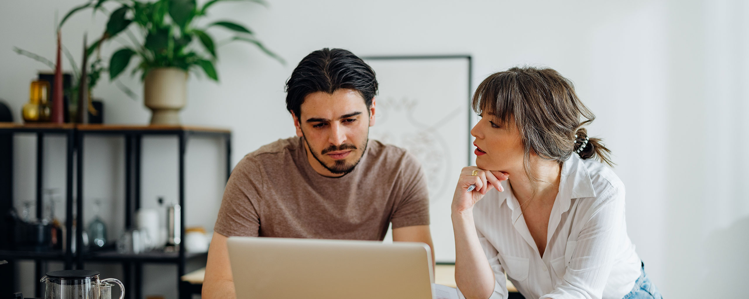 Two people looking at a laptop while considering a 401(k) hardship withdrawal.