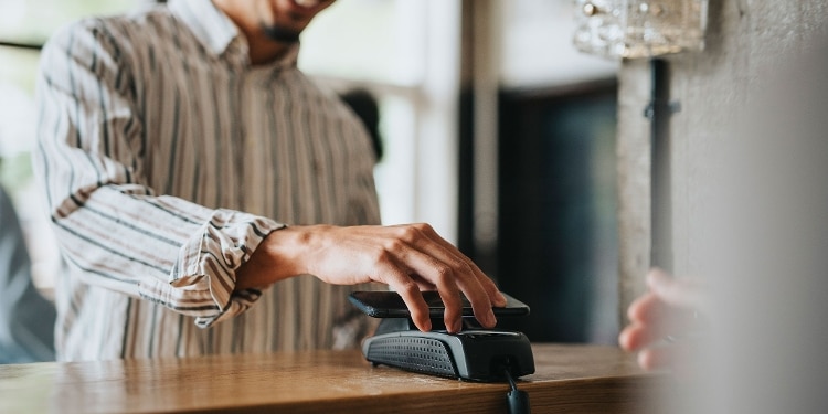 Someone using their phone to tap to pay.