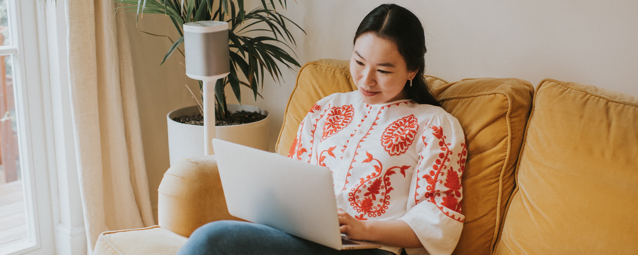 A person sitting on their couch and looking at their laptop considers ways to be financially responsible.