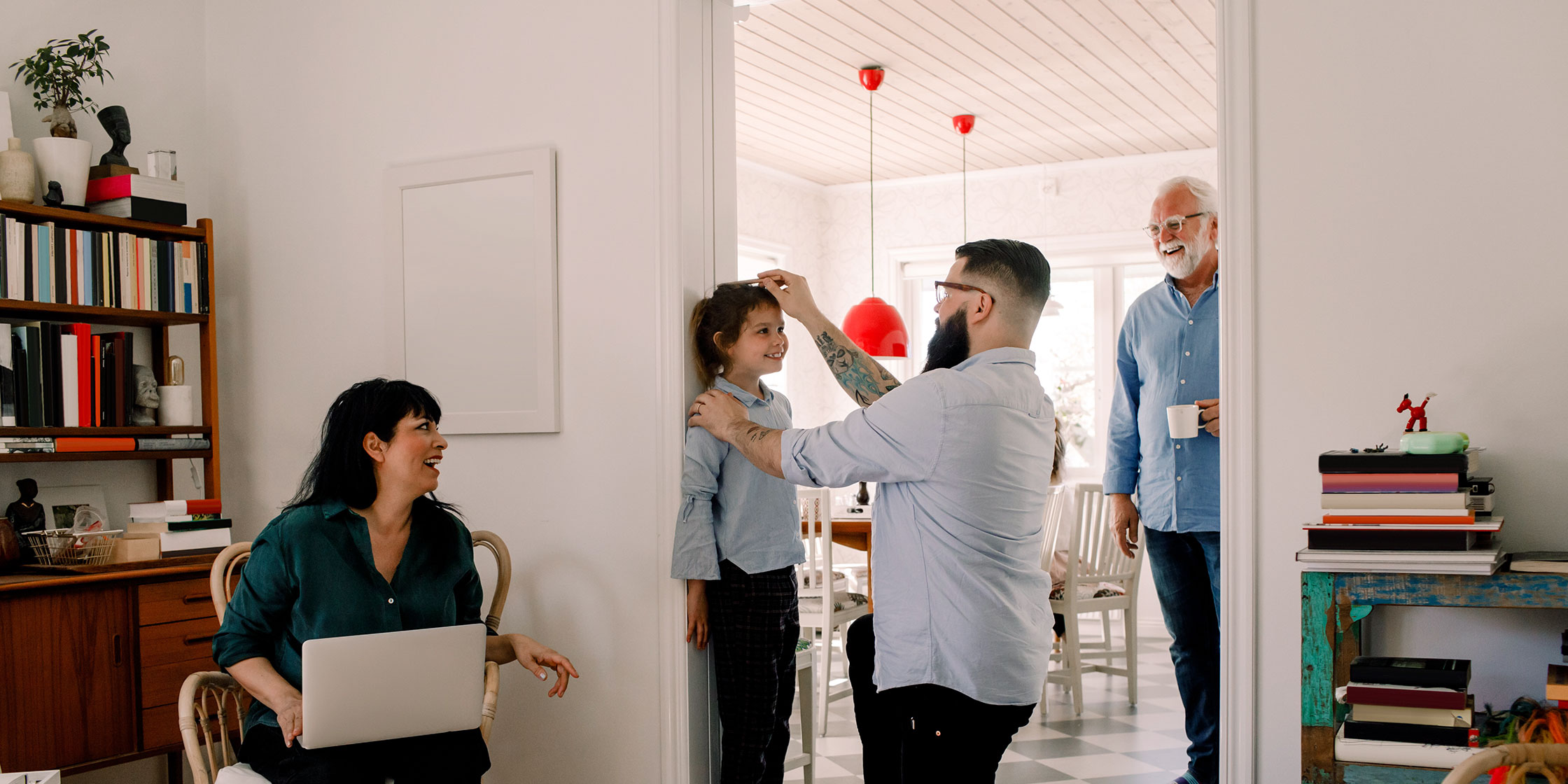 A family gathers in the living room to mark a young girl’s height on a doorway.