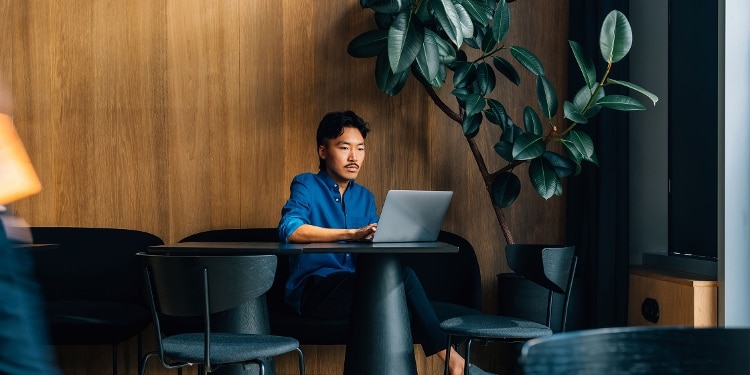A person focuses on a laptop while sitting at a table in a casual and relaxed atmosphere.