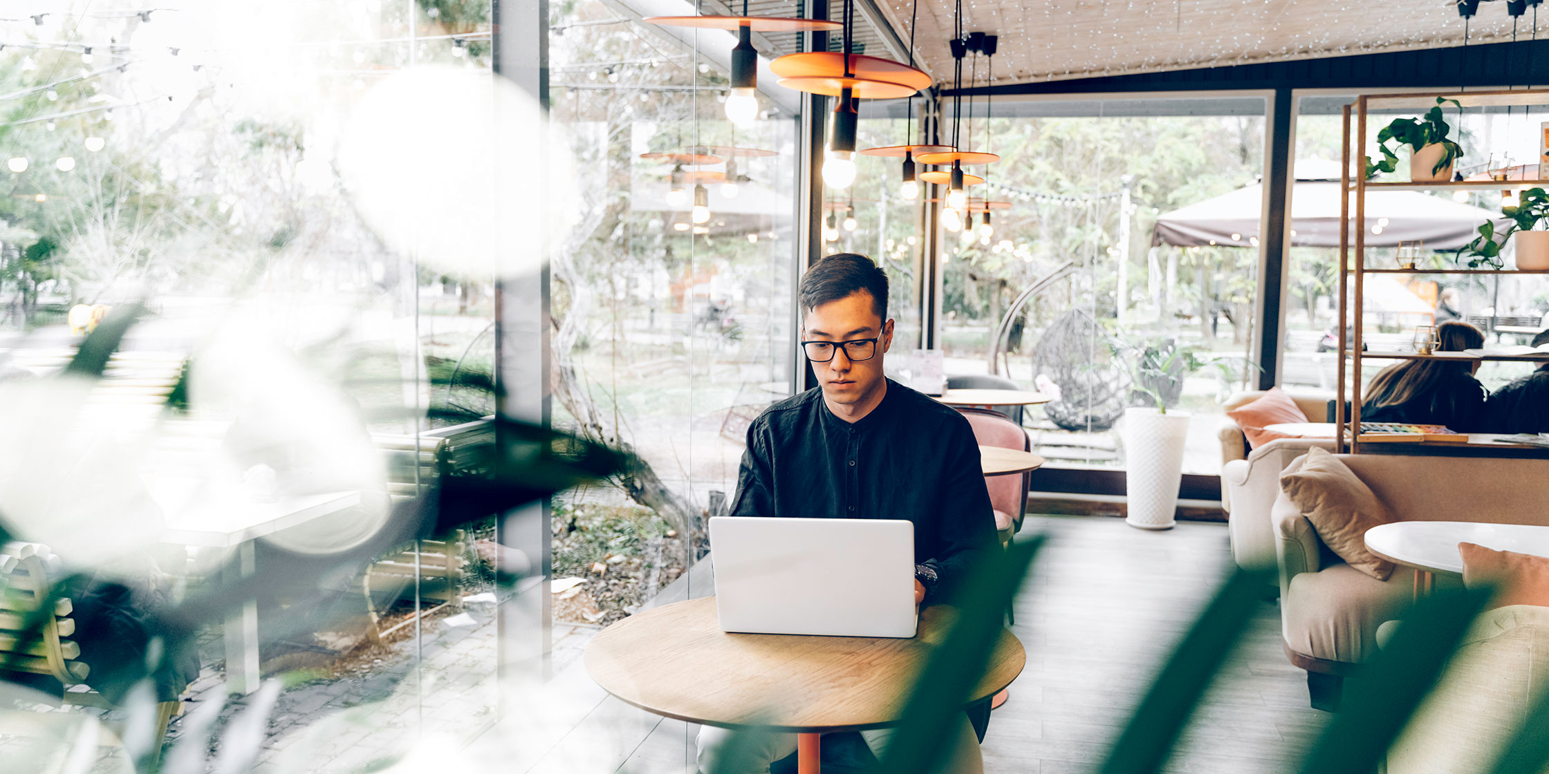 A person with bad credit sits in a coffee shop using a laptop to apply for a credit card.