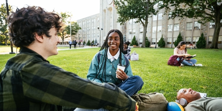 Students relax on a grassy area in front of a university building.