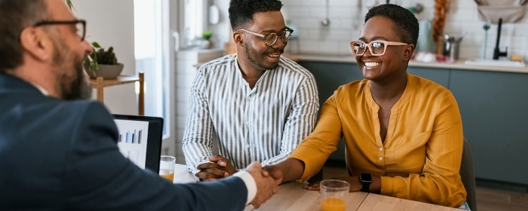 A smiling couple talking to a certified financial planner (CFP).