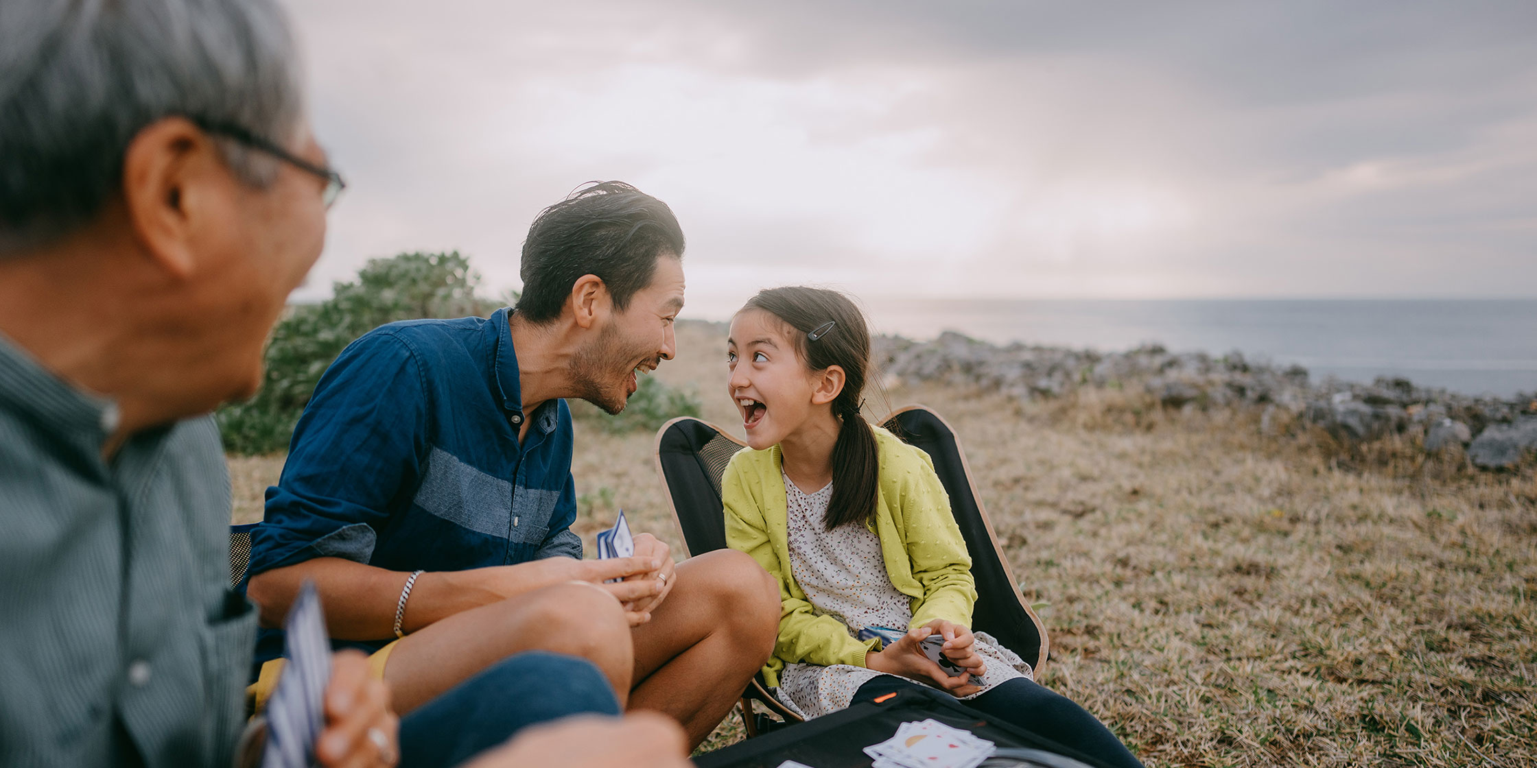 A grandfather looks as a father and his daughter share a funny moment.
