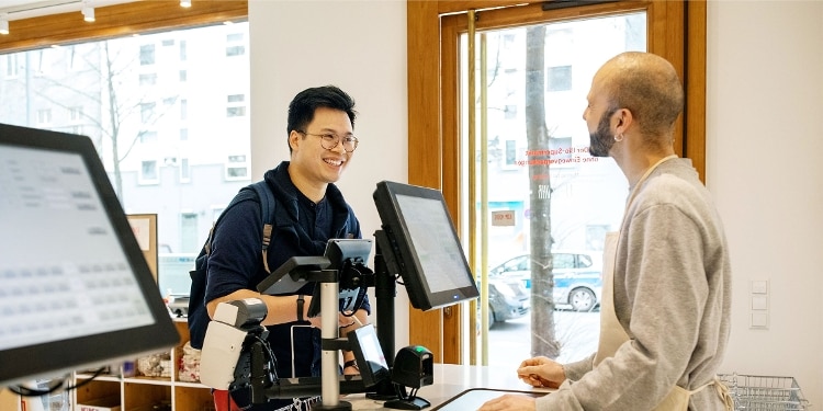 A person wearing glasses checks out at a coffee shop.