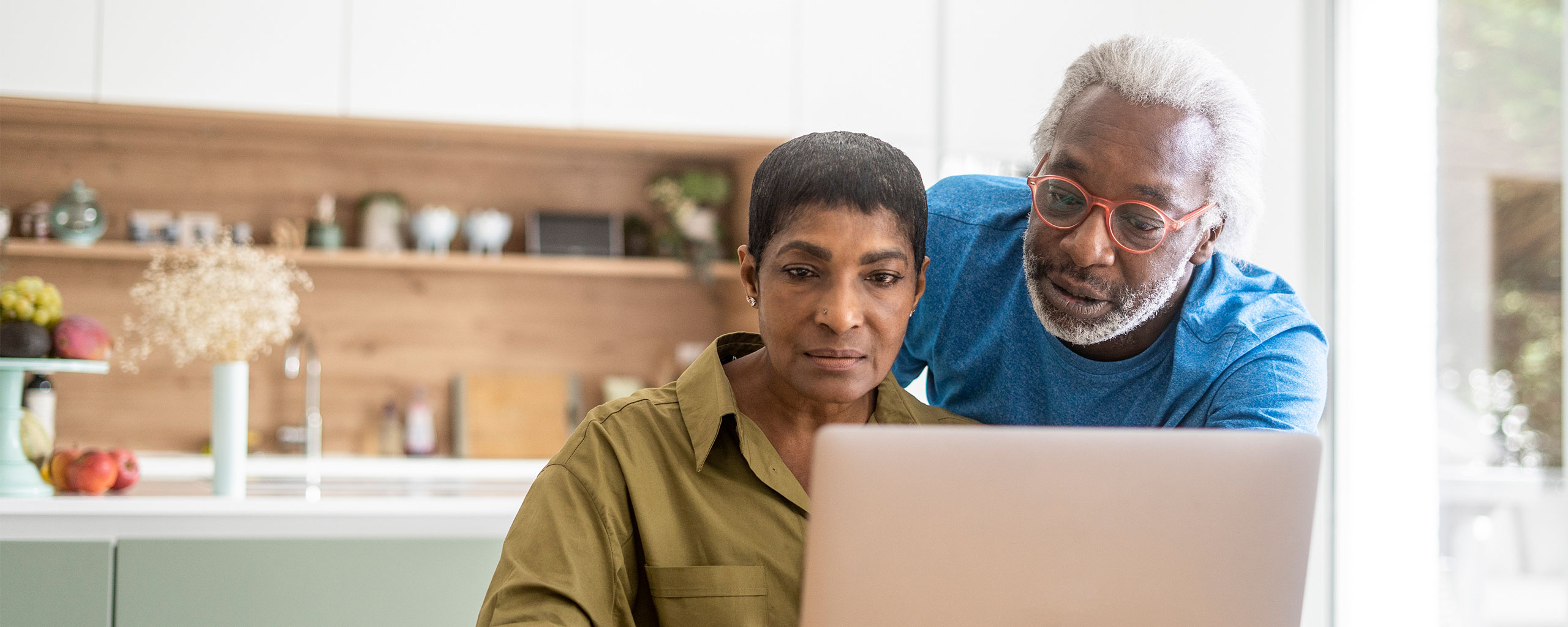 Two people look at an open laptop screen together.