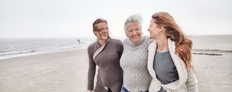 A family of three walking together on the beach.