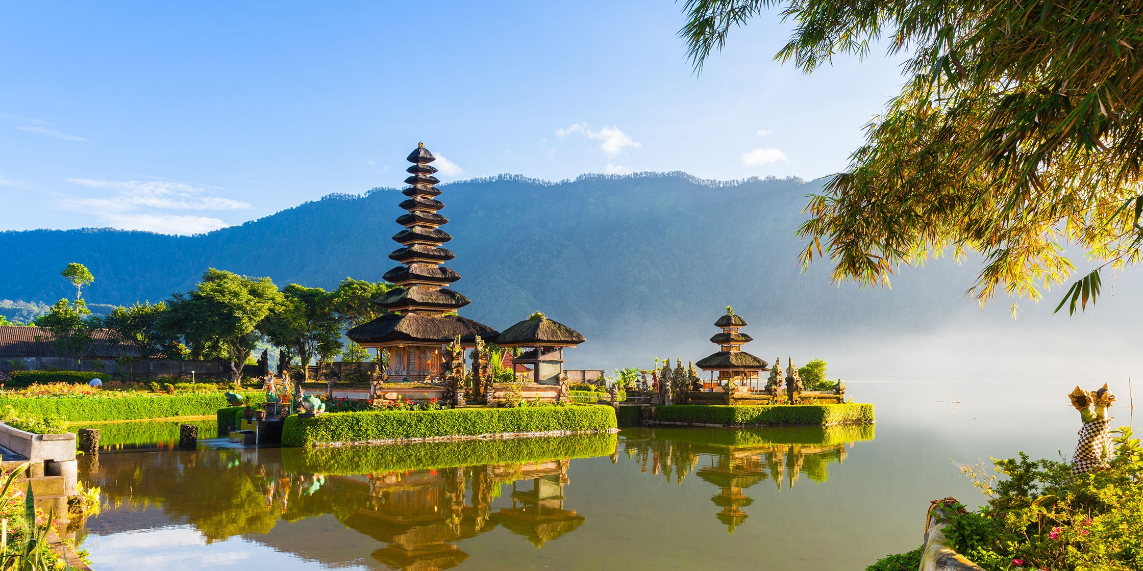 Pura Ulun Danu Bratan at sunrise. A temple on a lake with lush vegetation and mountains in the background in Bedugul, Bali, Indonesia.