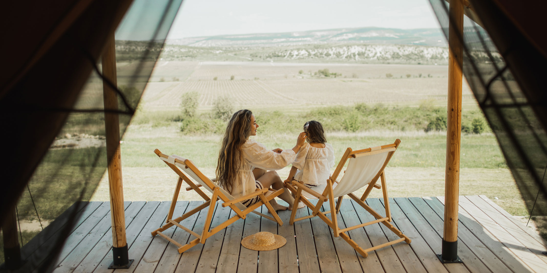 A mother and child sit on a deck during a glamping vacation.
