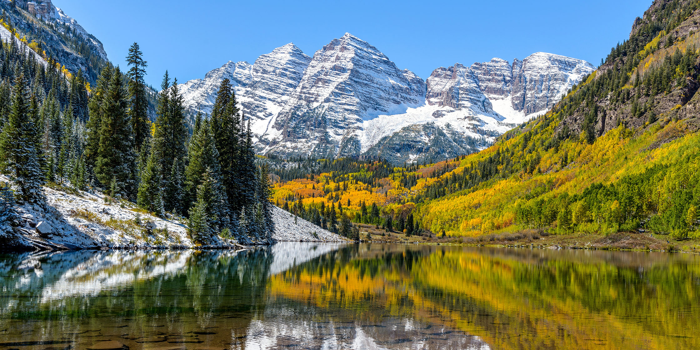 Autumn midday view of snow-coated Maroon Bells reflecting in crystal clear Maroon Lake, Aspen, Colorado