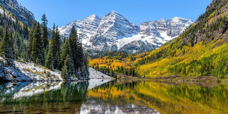 Autumn midday view of snow-coated Maroon Bells reflecting in crystal clear Maroon Lake, Aspen, Colorado