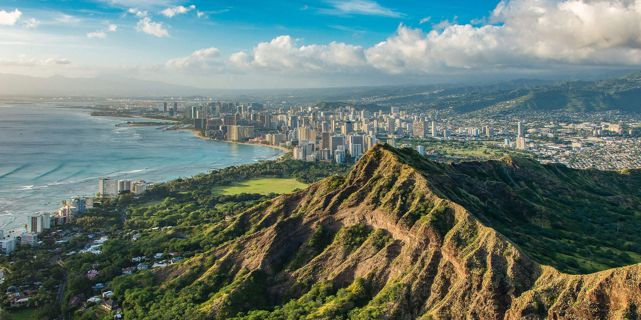 An aerial view of Diamond Head crater in Oahu, Hawaii, with Honolulu in the distance.