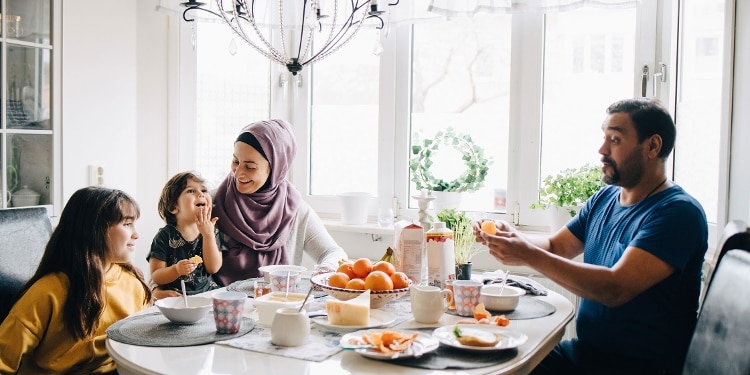 A happy family eating breakfast at their dining room table.