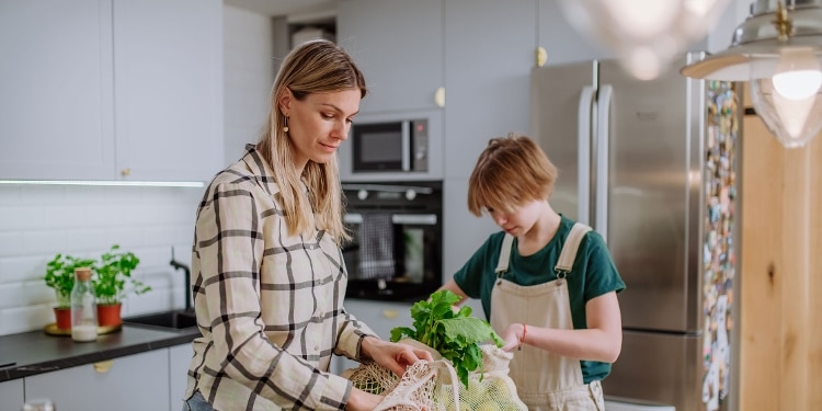 A photo of a parent and child putting away groceries, which are typically included in a household budget.