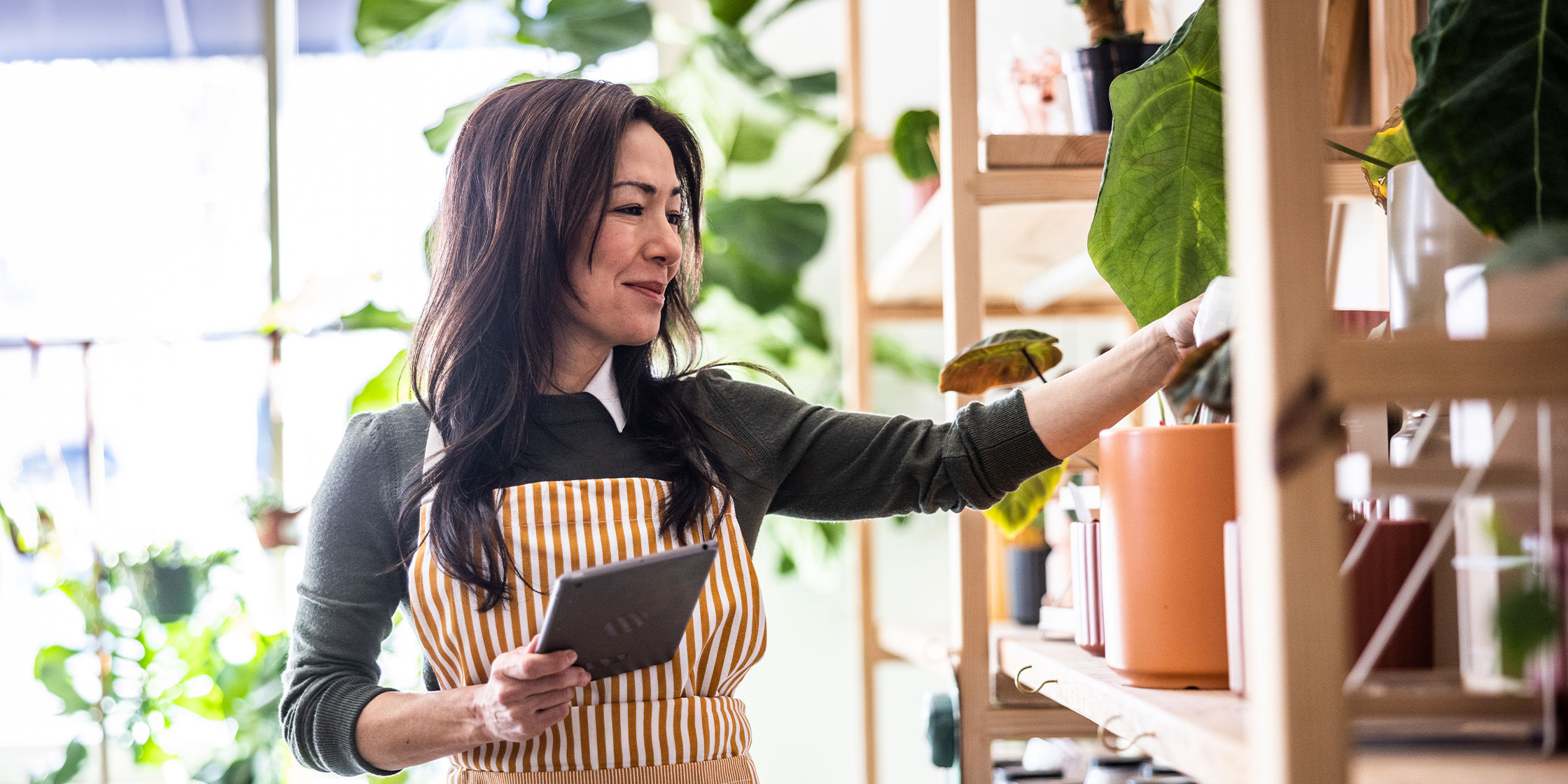 Person tends to indoor plants and earns active income while working at a garden center.