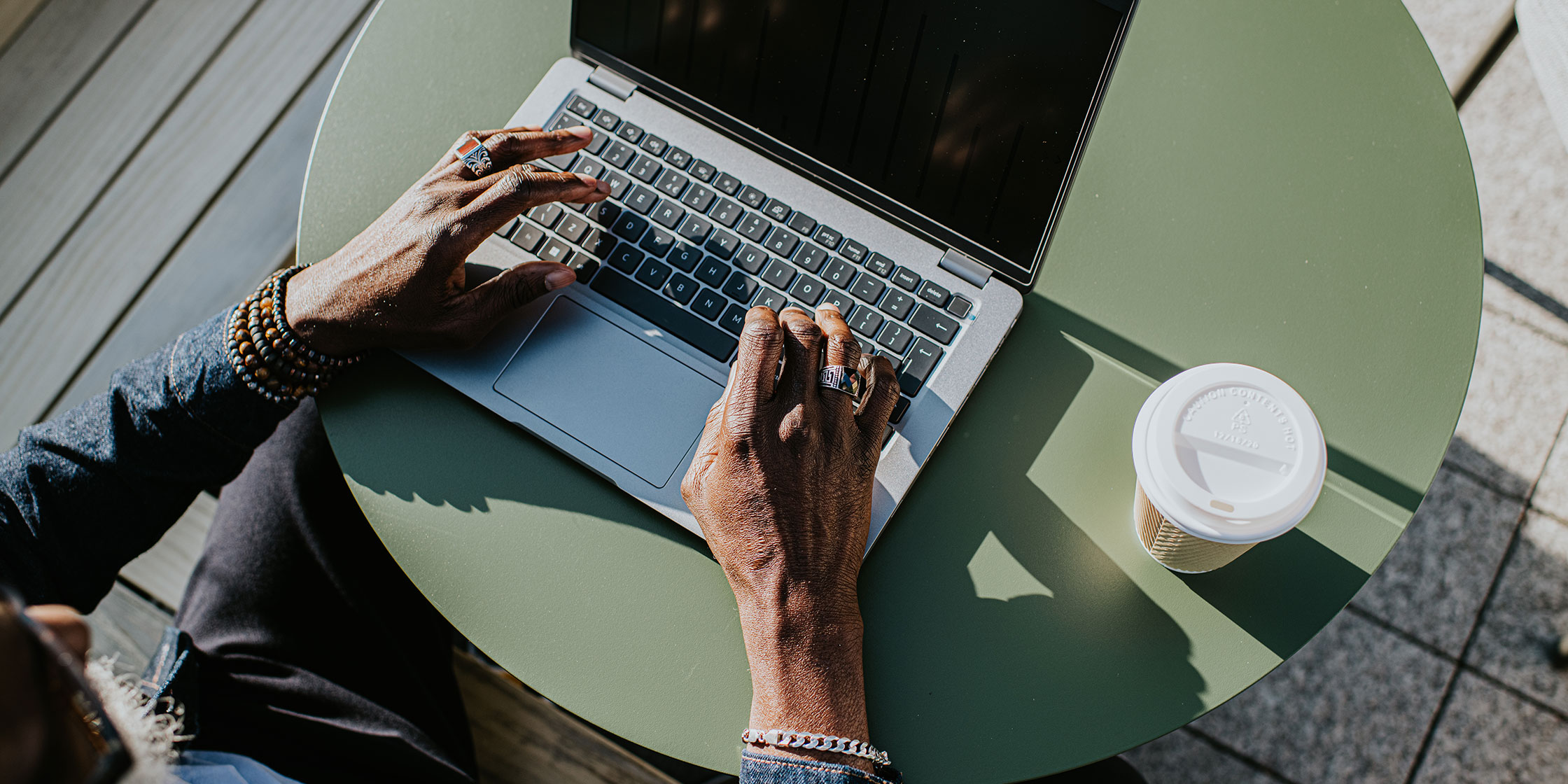 A person sits on a shadowy patio and uses a laptop to understand how bankruptcies are reflected in credit reports.