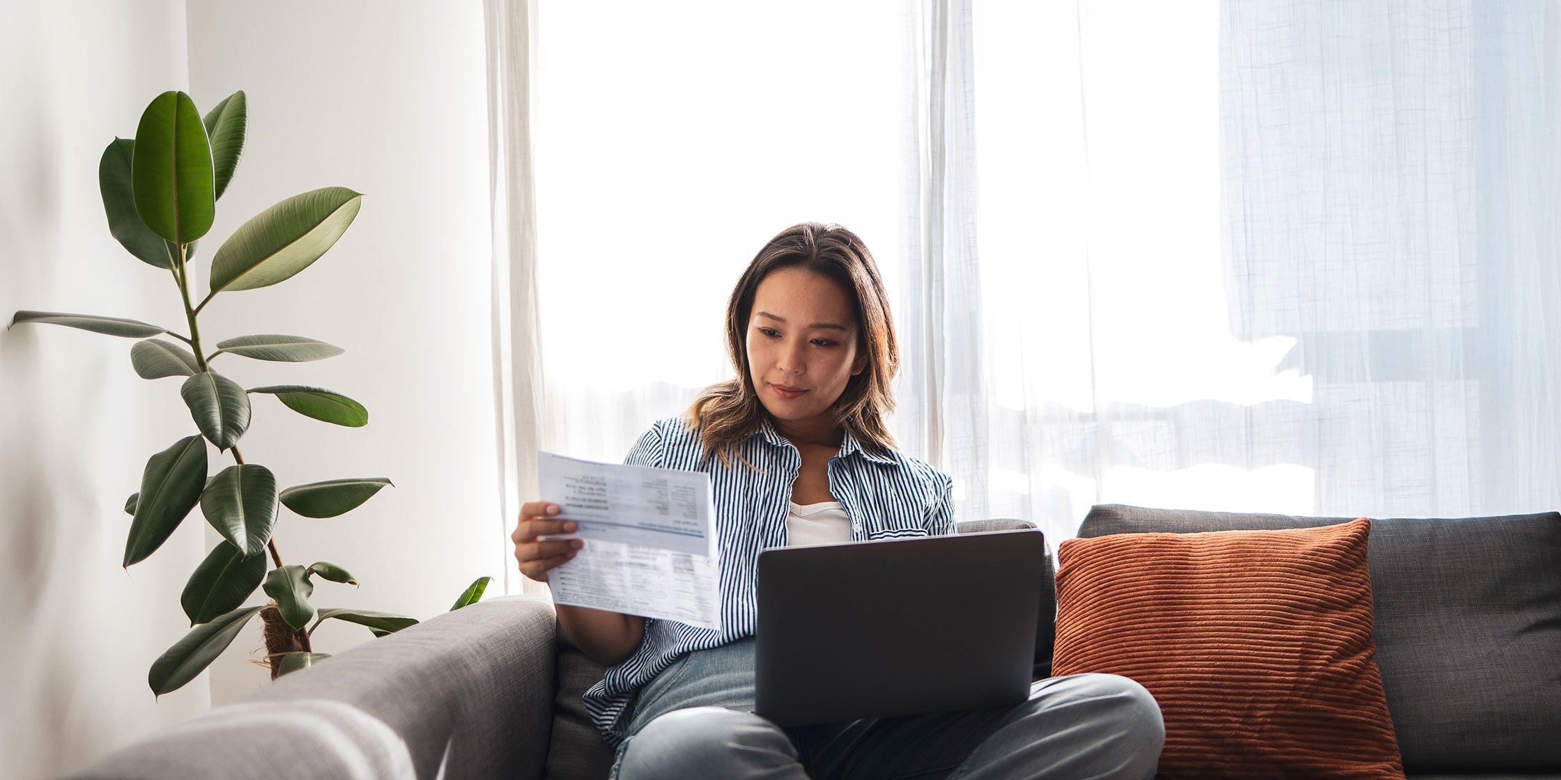 A person sits at a laptop reviewing their credit card statement.