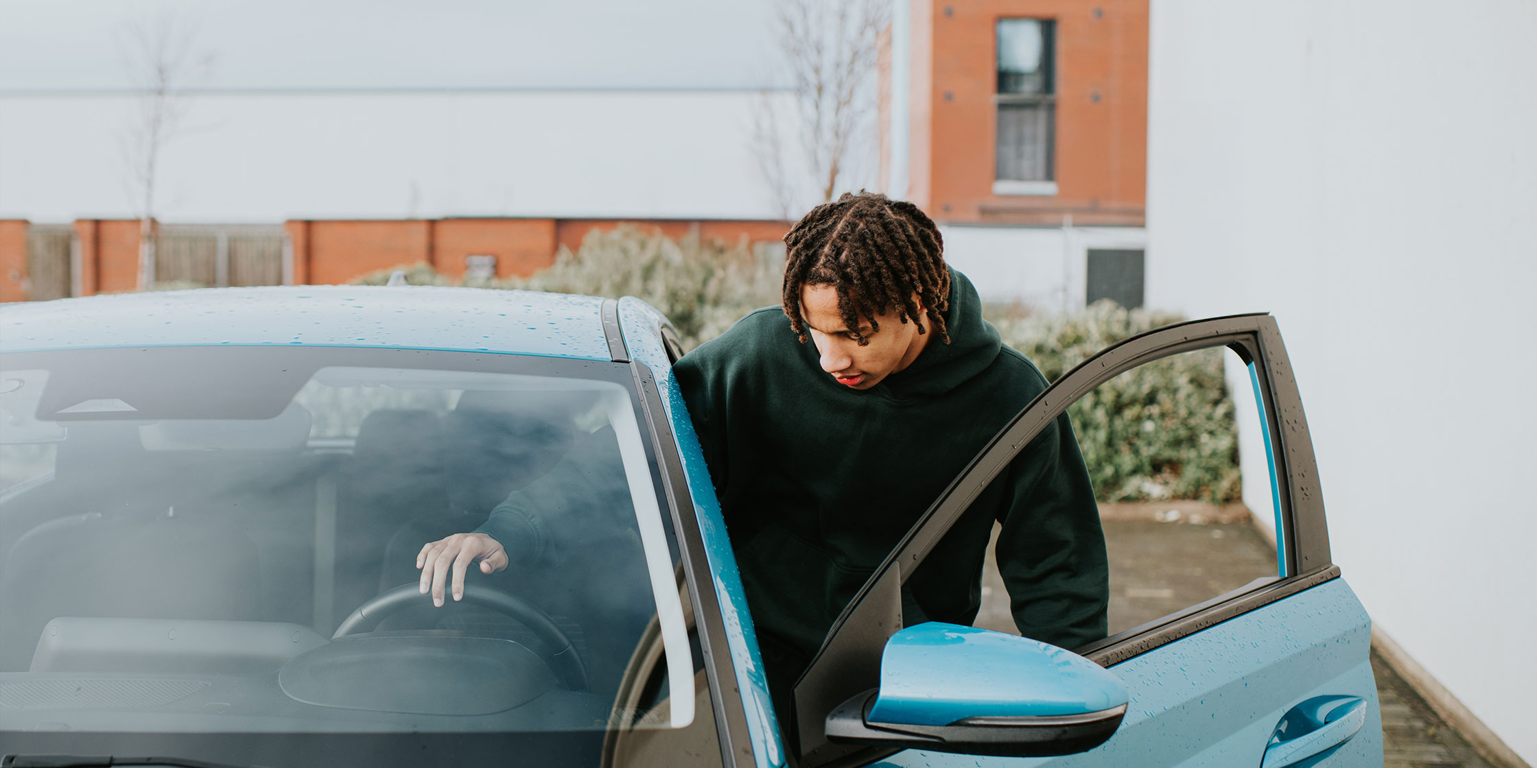 Young person steps into a car.