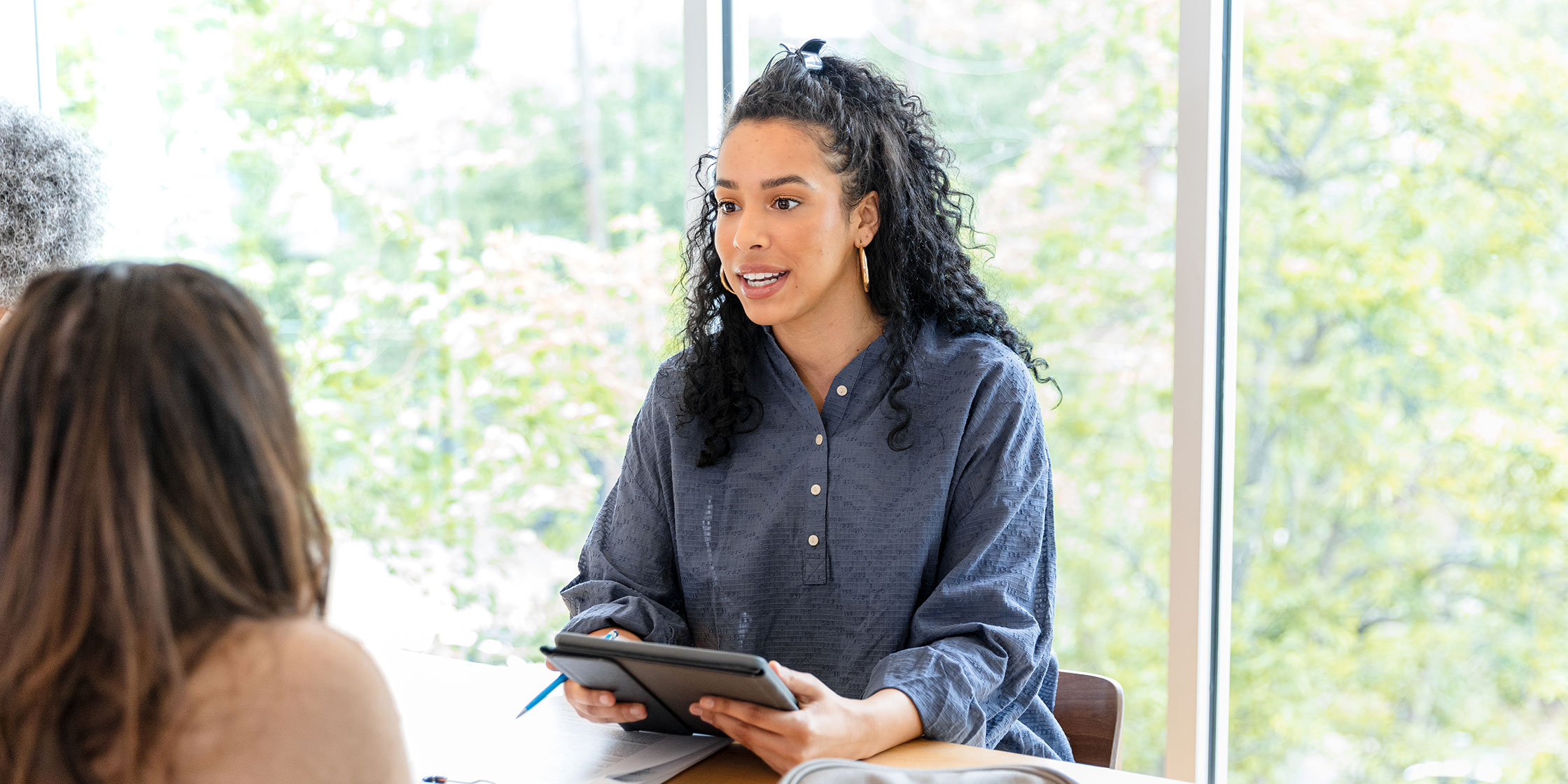 A credit union representative sits opposite two customers at a desk.