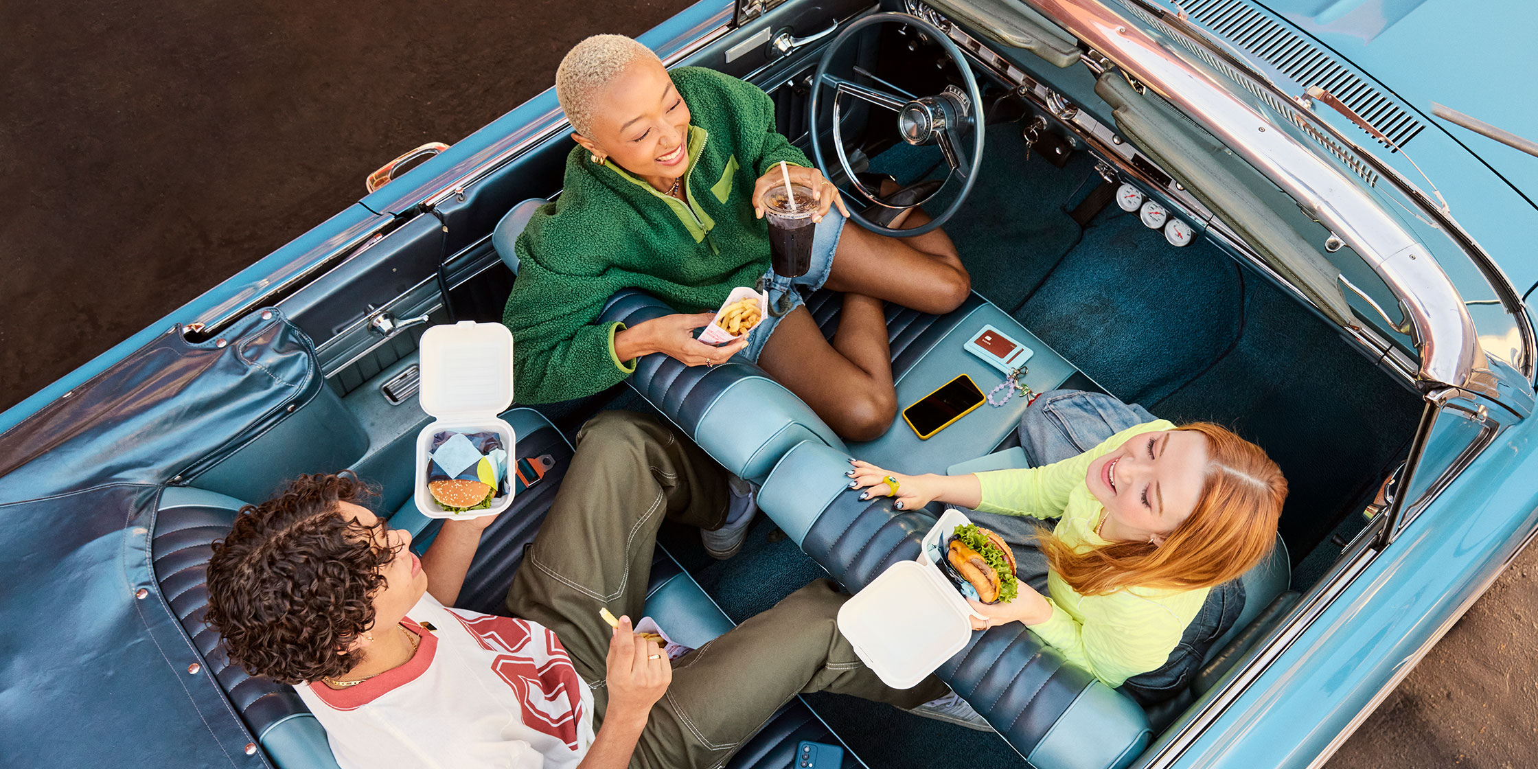 College students laughing while waiting together in a convertible.