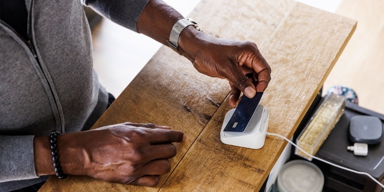 A person tapping to pay at checkout with their contactless EMV chip card.