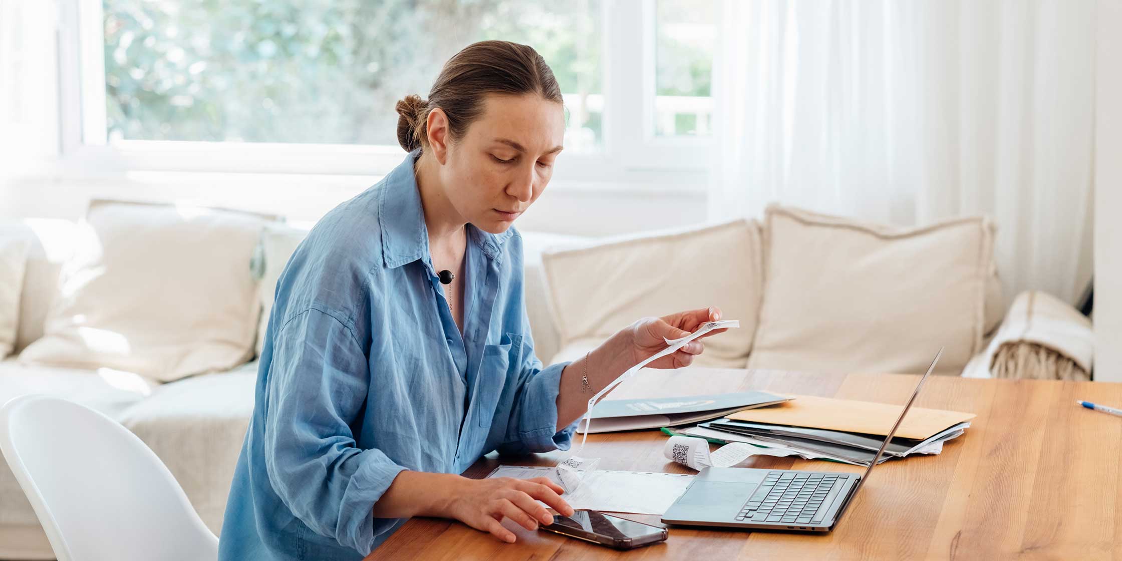 A person sitting at a desk and working on their phone and laptop.
