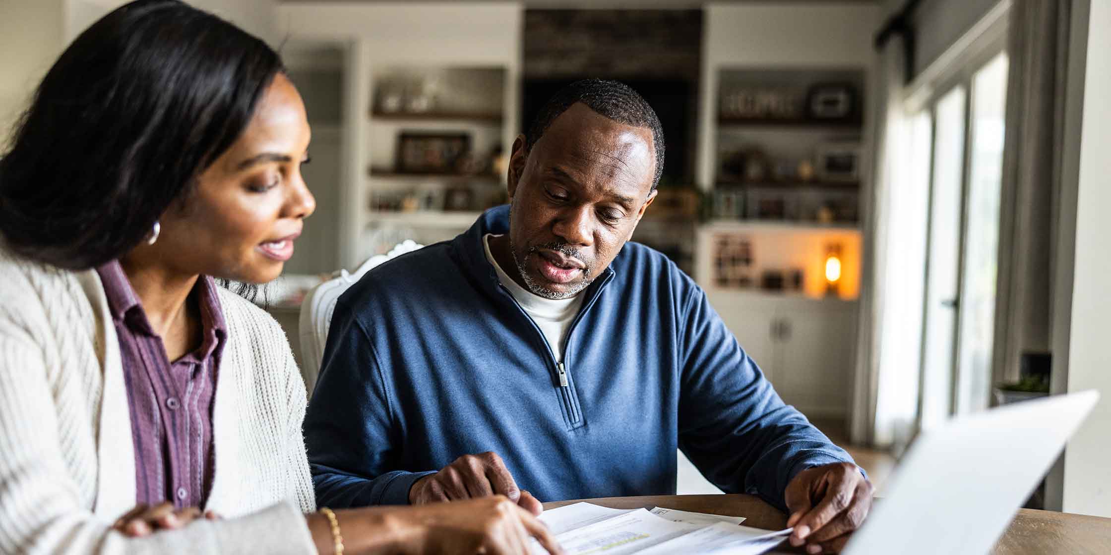 Two adults review estate paperwork at a table in their home