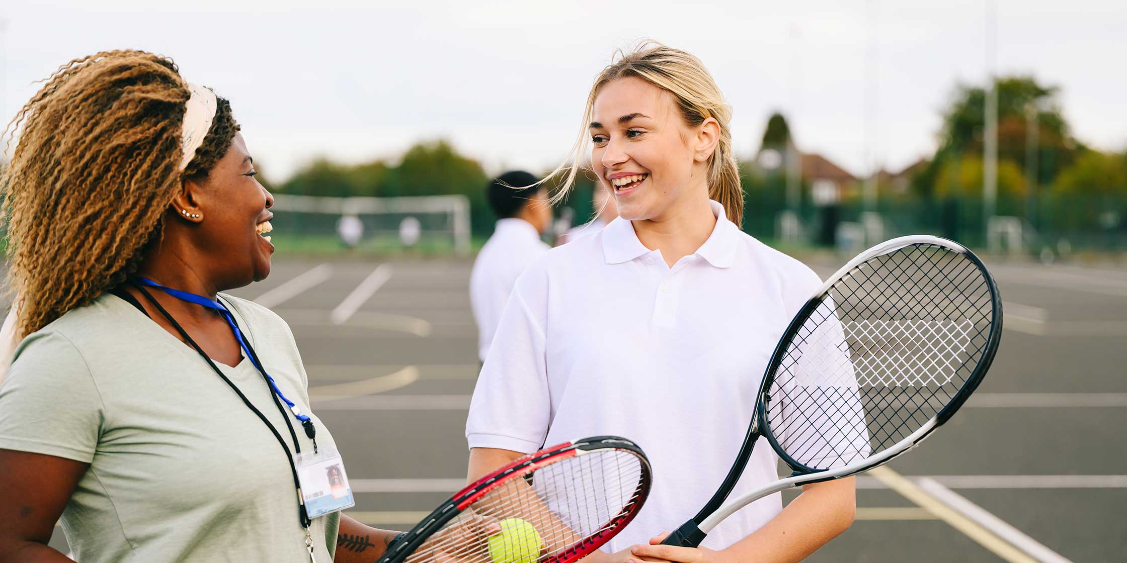 Two people standing on a tennis court holding tennis racquets.