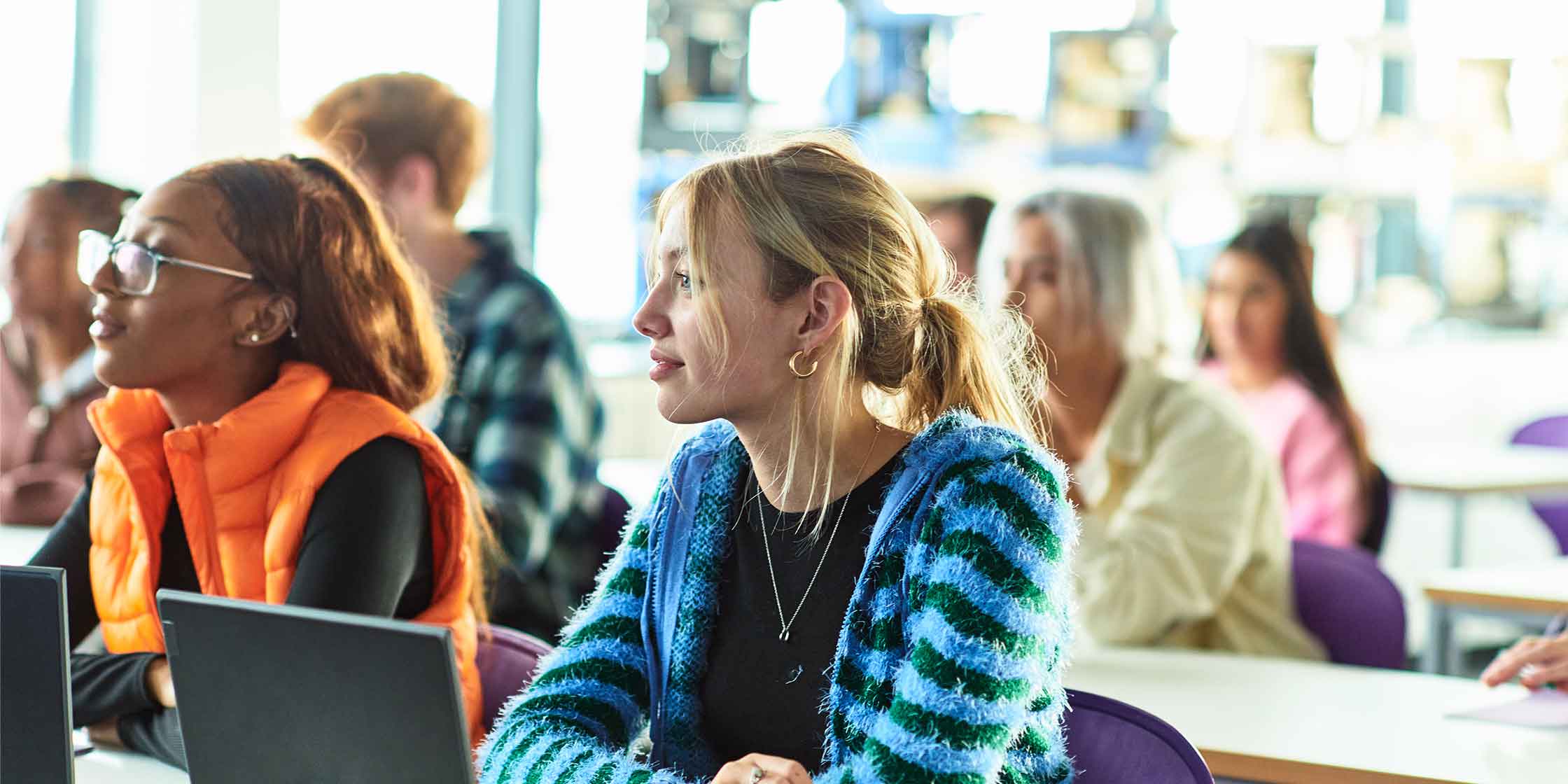 Students sitting in class with open laptops in front of them.