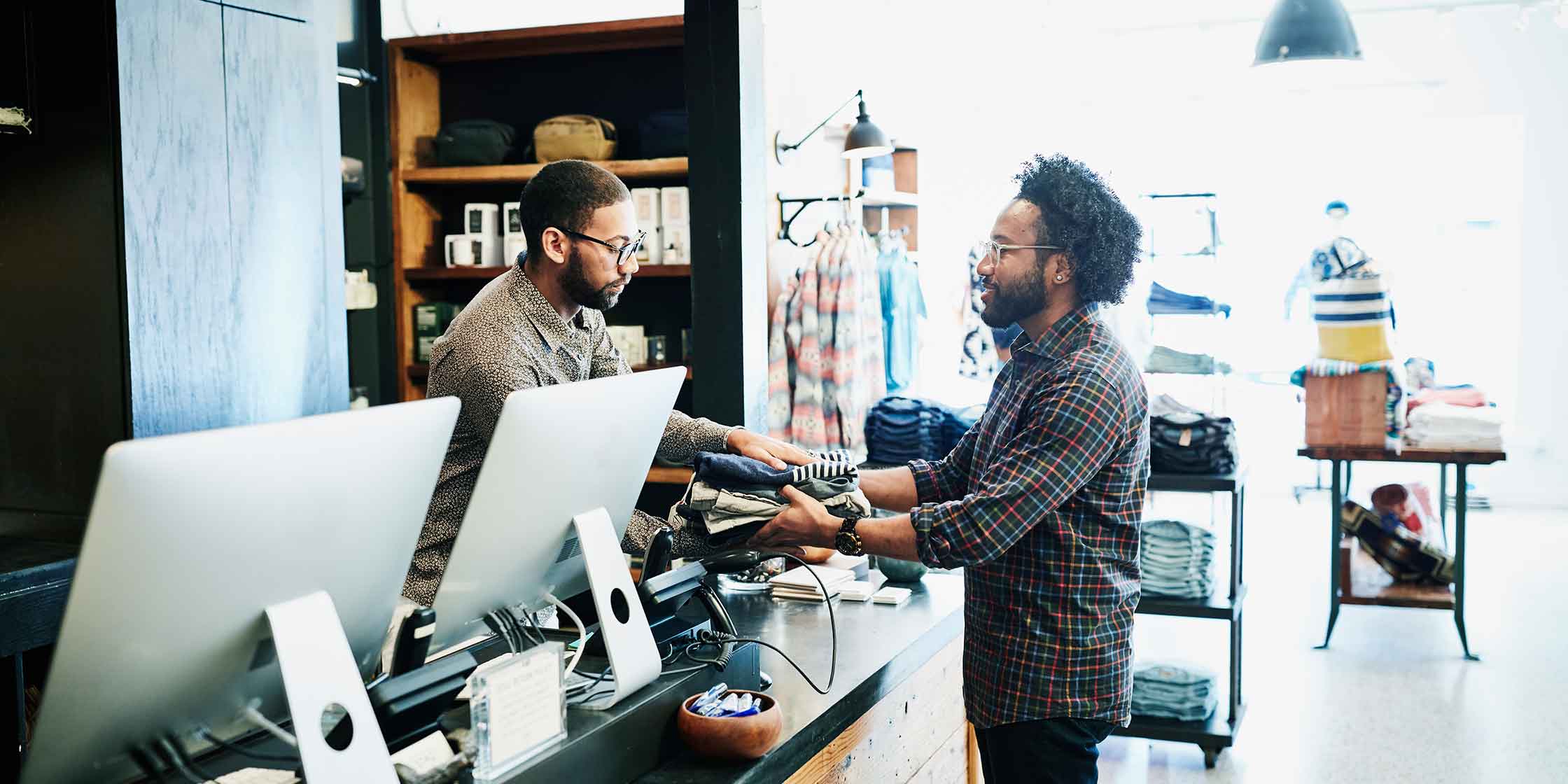 A photo of a person buying clothes in a retail store. They’re paying the cost of their items plus sales tax.