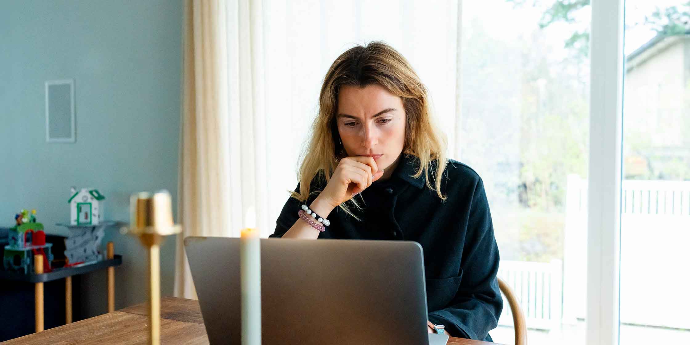 A person sitting at a table and looking at their laptop.