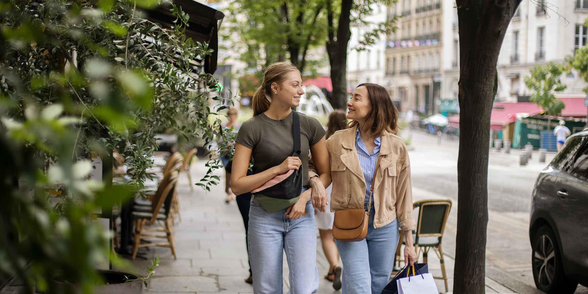 Two people walk down a city street on a shopping trip, paying for their purchases with their Capital One credit cards.