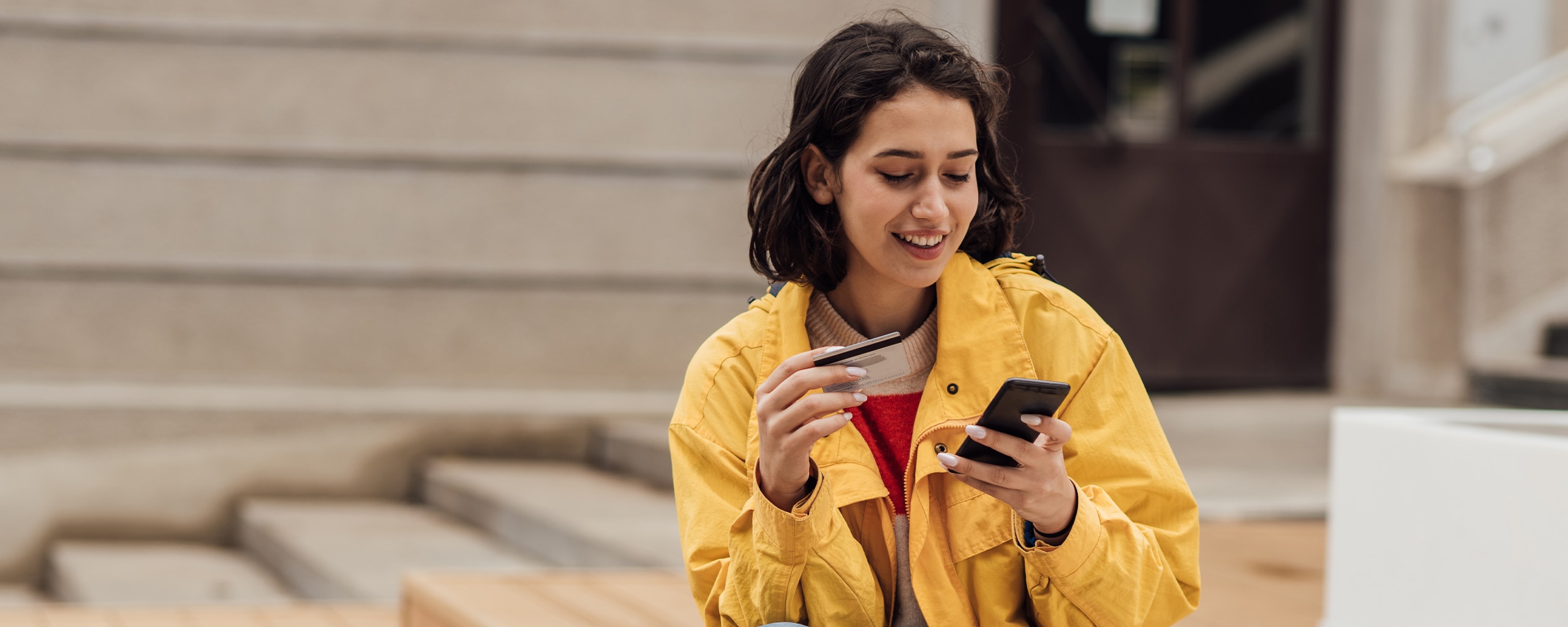 A smiling person looking at their credit card balance on their phone.